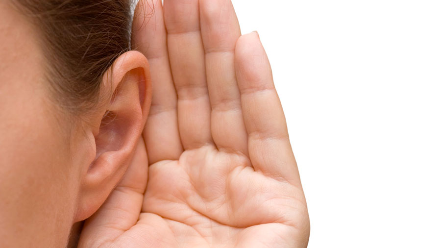 mujer con mano en oído para escuchar mejor