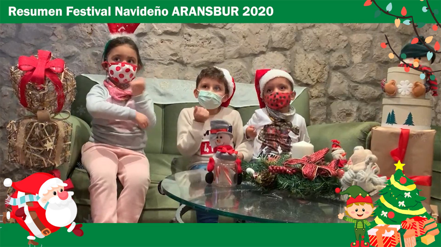 Niños disfrazados de Papá Noel en frente de una chimenea de piedra